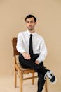 Professional Man Sitting on Wooden Chair in Studio