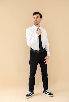 Stylish man in white shirt and tie poses against a neutral backdrop. Perfect for fashion or professional portfolio.