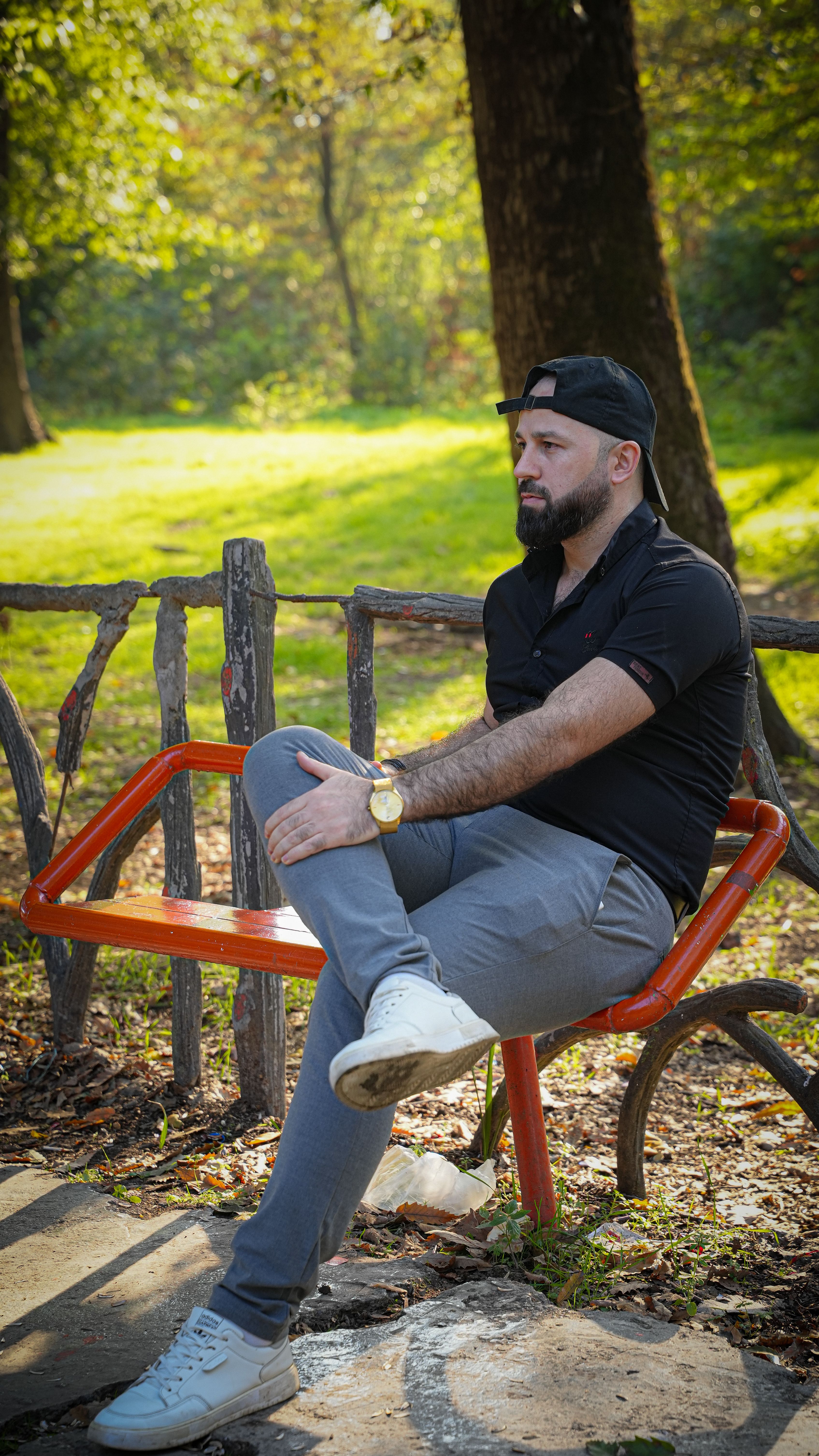 A man in casual attire relaxes on a park bench amidst a beautiful autumn forest setting.