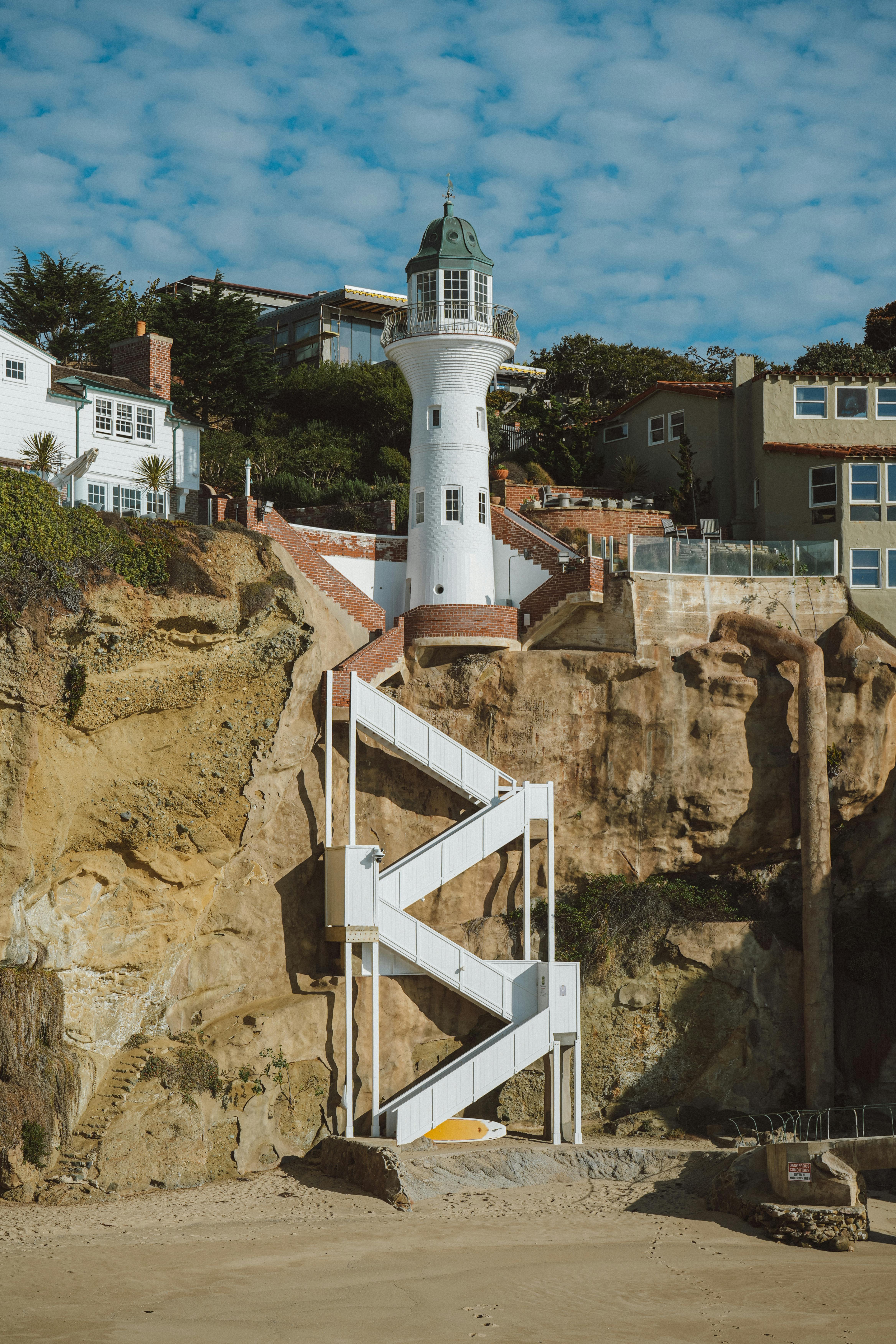 White lighthouse standing tall on a scenic cliffside with blue sky.
