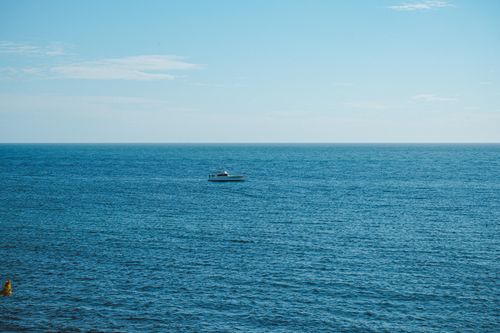 Free Peaceful scene of a lone boat on the clear blue sea under a bright sky Stock Photo