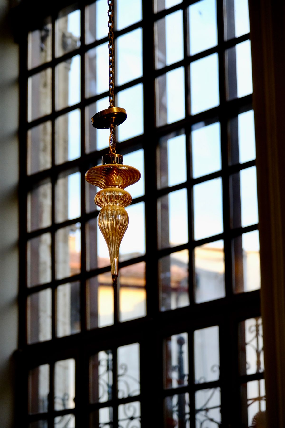 A glass pendant chandelier in a shadowed period corridor