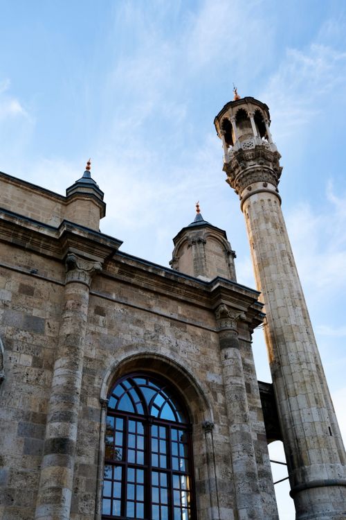 Free View of a historic mosque's facade with minaret under a clear blue sky. Stock Photo