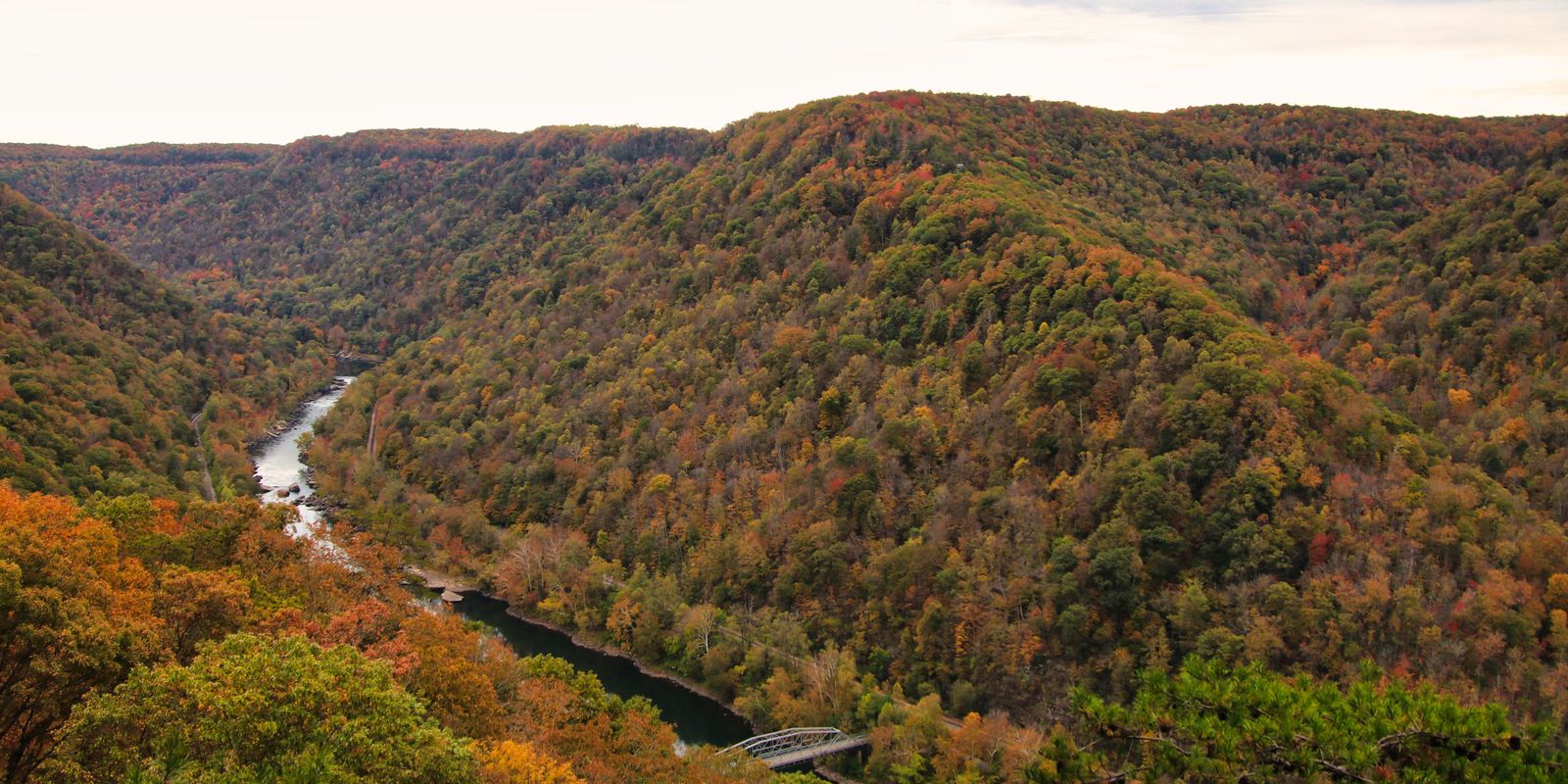 Panoramic view of a river winding through a lush autumn valley