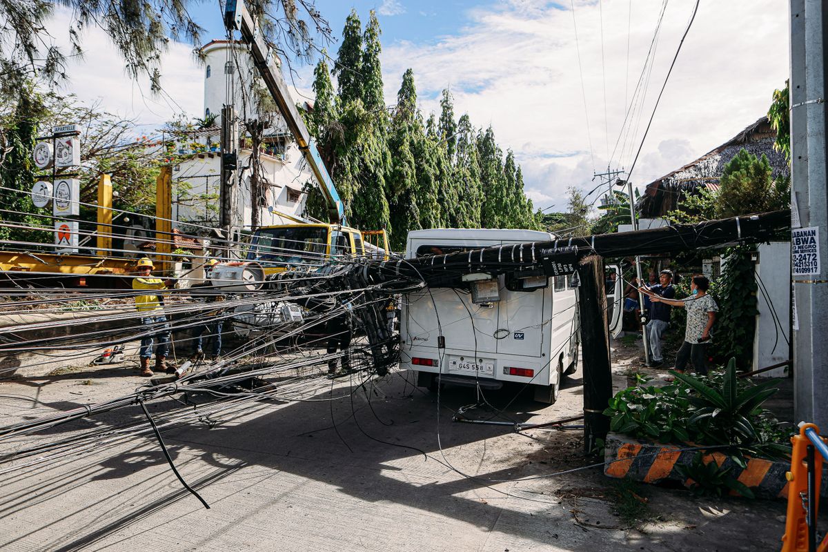 Utility crew repairing damaged power lines on a street after storm damage in Southeast Asia