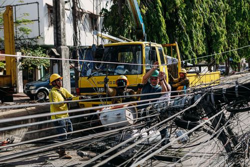 Free Utility workers conduct repairs on fallen power lines with heavy machinery on a sunny day. Stock Photo