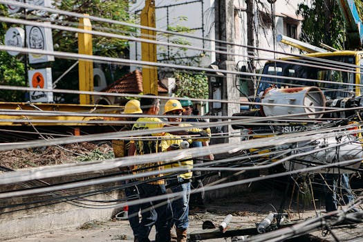 Photo by Denniz Futalan Utility workers repairing downed power lines amidst damaged infrastructure. Outdoor setting with chaos.