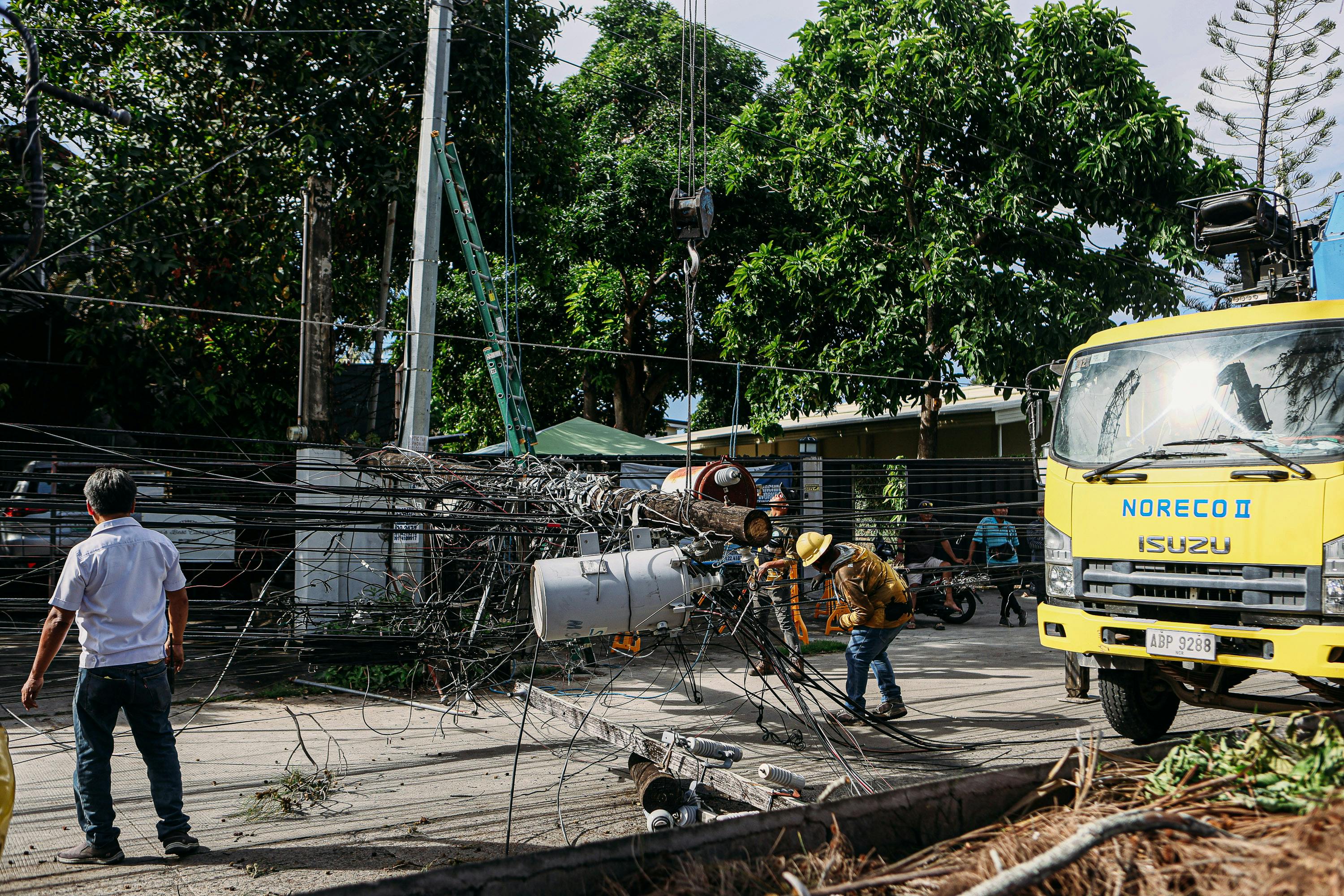 Team of workers in hard hats repairing electrical lines from a fallen pole after an accident.