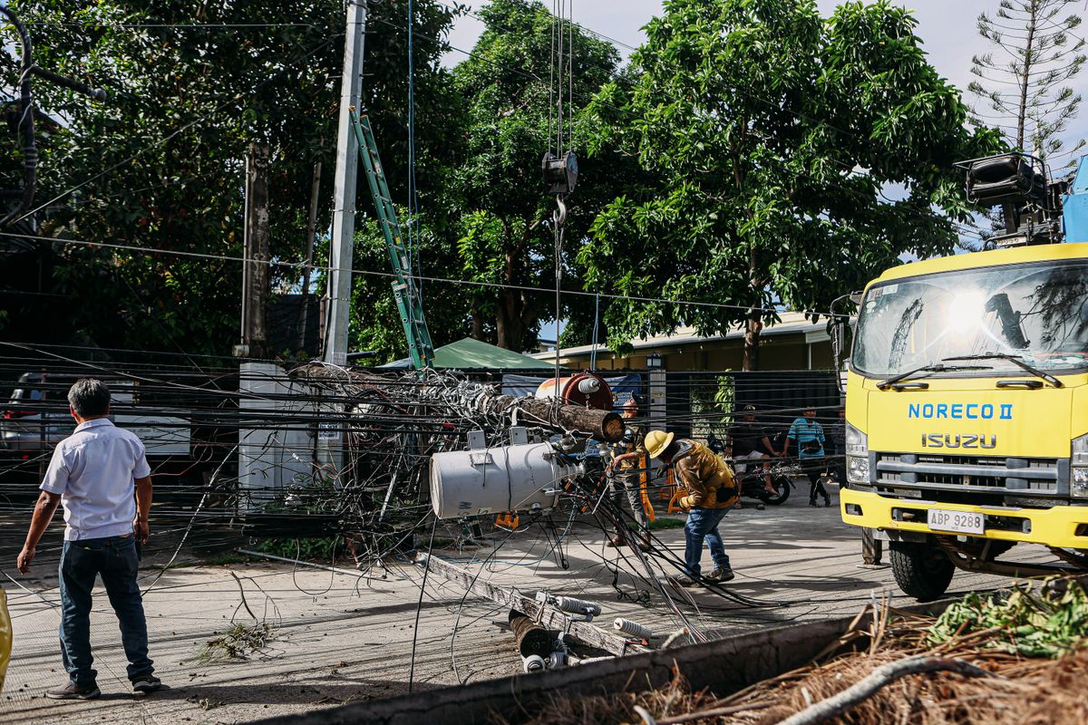 Emergency crew in hard hats repairing electrical lines from a downed utility pole
