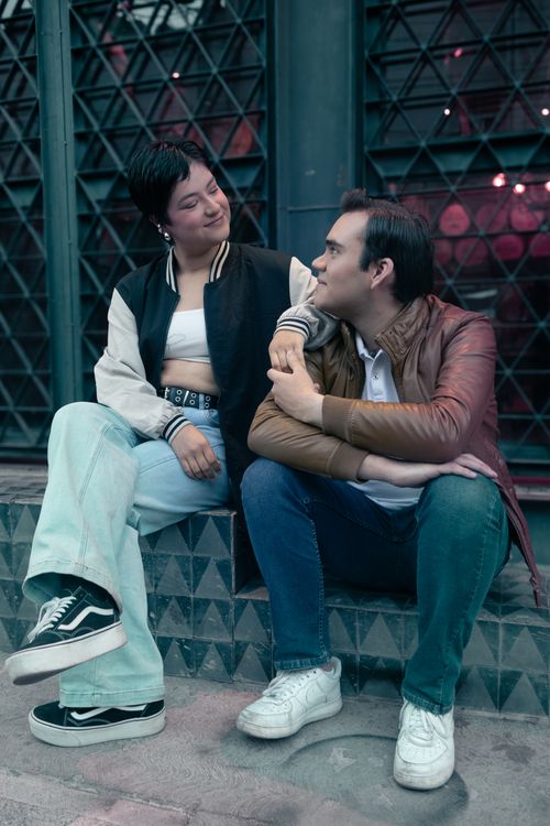 Free A man and woman in casual attire sit and converse on an urban street in Aguascalientes, Mexico. Stock Photo