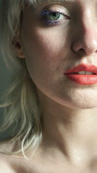 Close-up of a woman with striking makeup and vivid lips, artistic style.