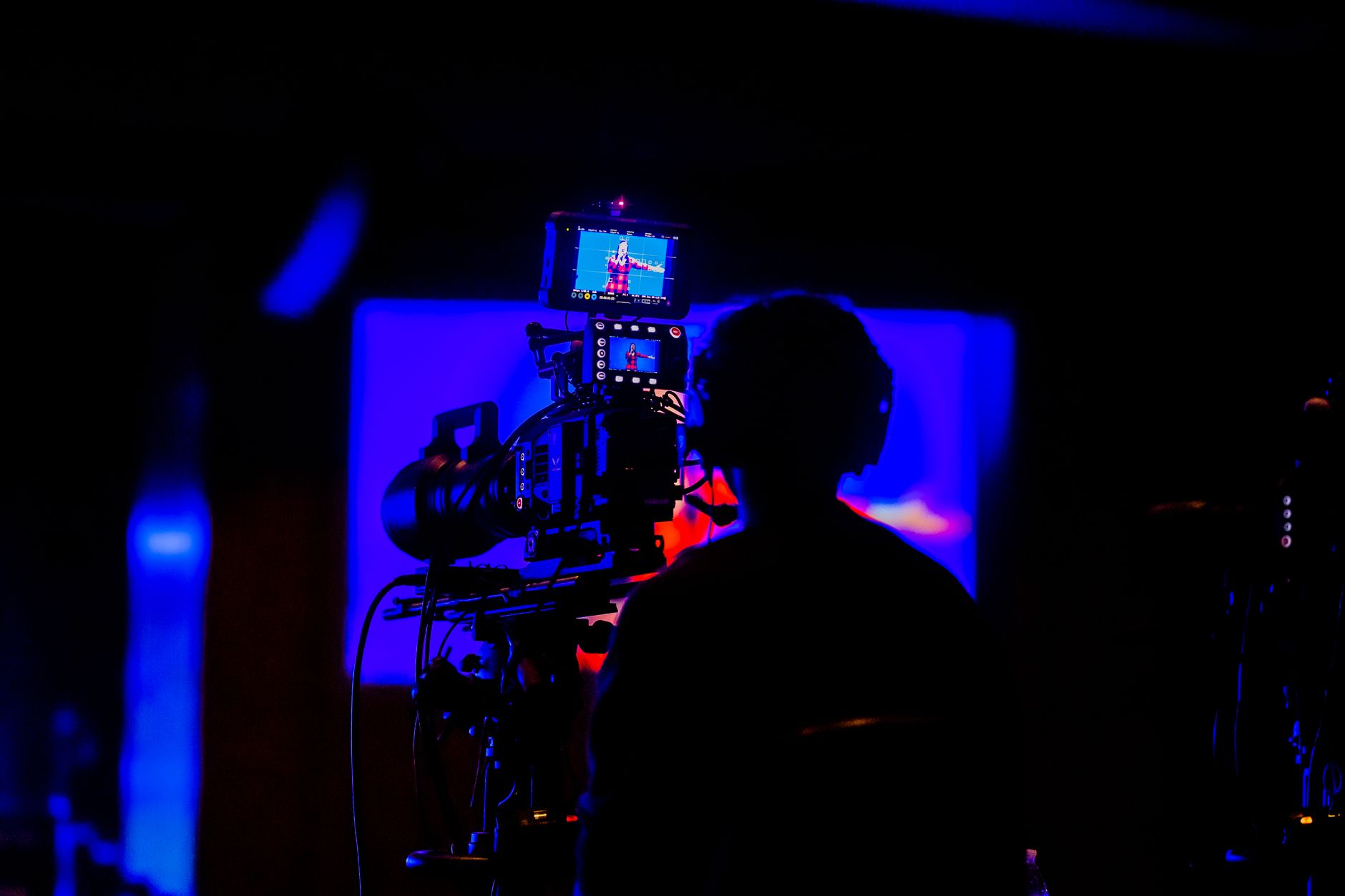 Cameraman capturing footage in low light during night event with vivid colors.