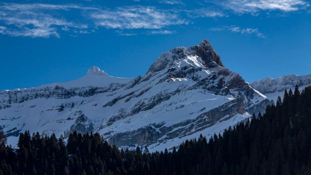 Breathtaking view of snow-covered Alpine mountains under a clear blue sky, ideal for winter travel and nature inspiration.