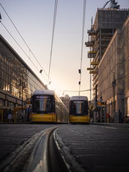Berlin's iconic yellow trams on Alexanderplatz with a sunset backdrop.