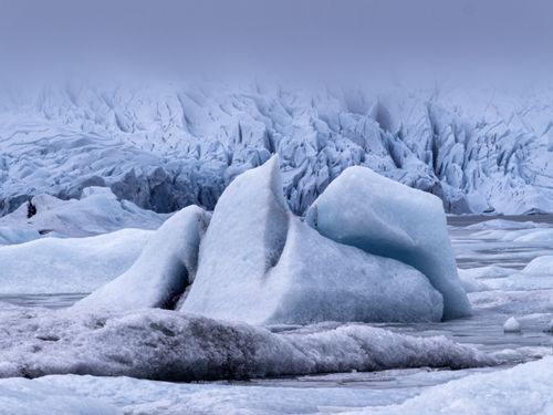 Free A breathtaking view of towering icebergs in a serene, frozen landscape under an overcast sky. Stock Photo