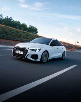 White Audi car driving on a highway in Ankara, Türkiye at sunset.