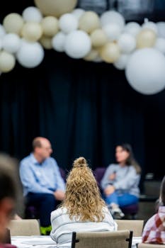 Attendees at a business seminar with speakers on stage and balloon decor theme.