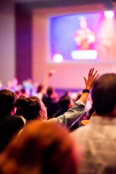 Vibrant concert scene with audience engaged, hand raised in excitement.