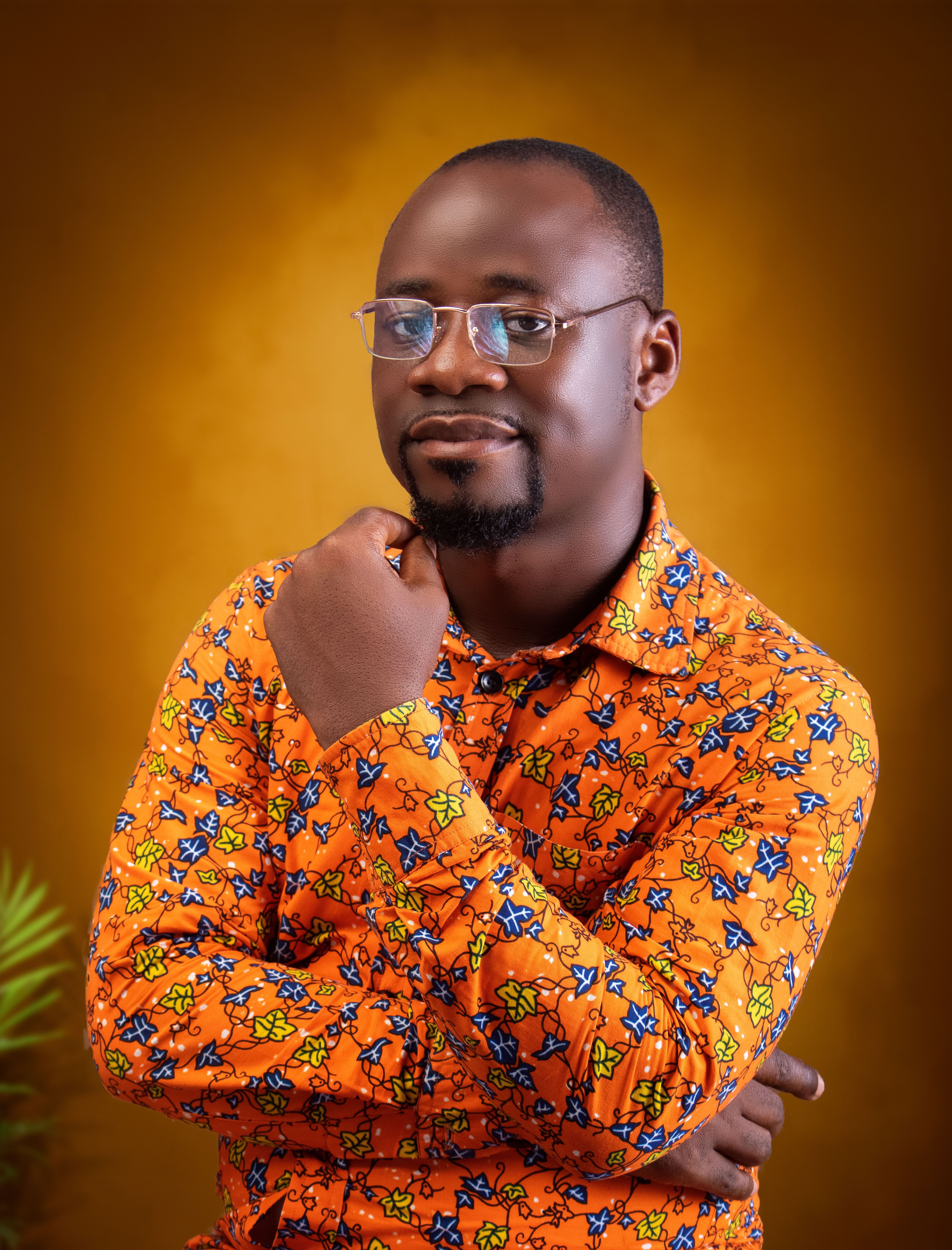 Confident man posing in bright African print shirt with bright background.