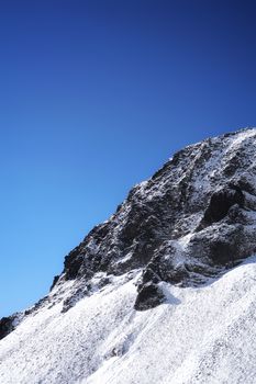 A striking view of a snow-covered mountain against a deep blue sky.