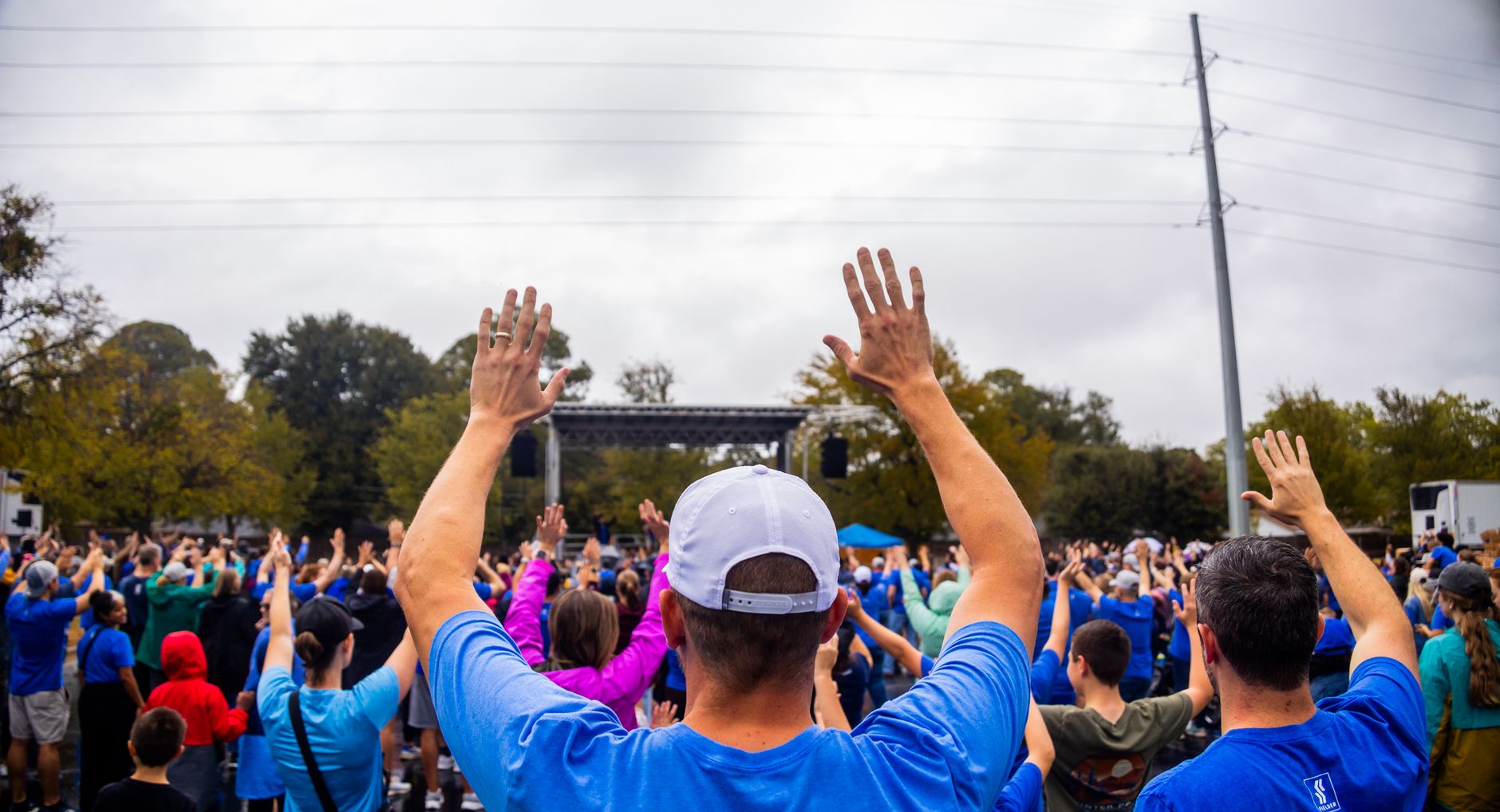A large group of people raising their hands at an outdoor community gathering