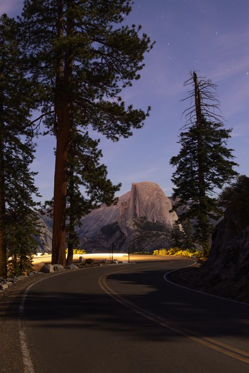 Free Captivating night scene of Half Dome framed by trees on a winding road in Yosemite. Stock Photo