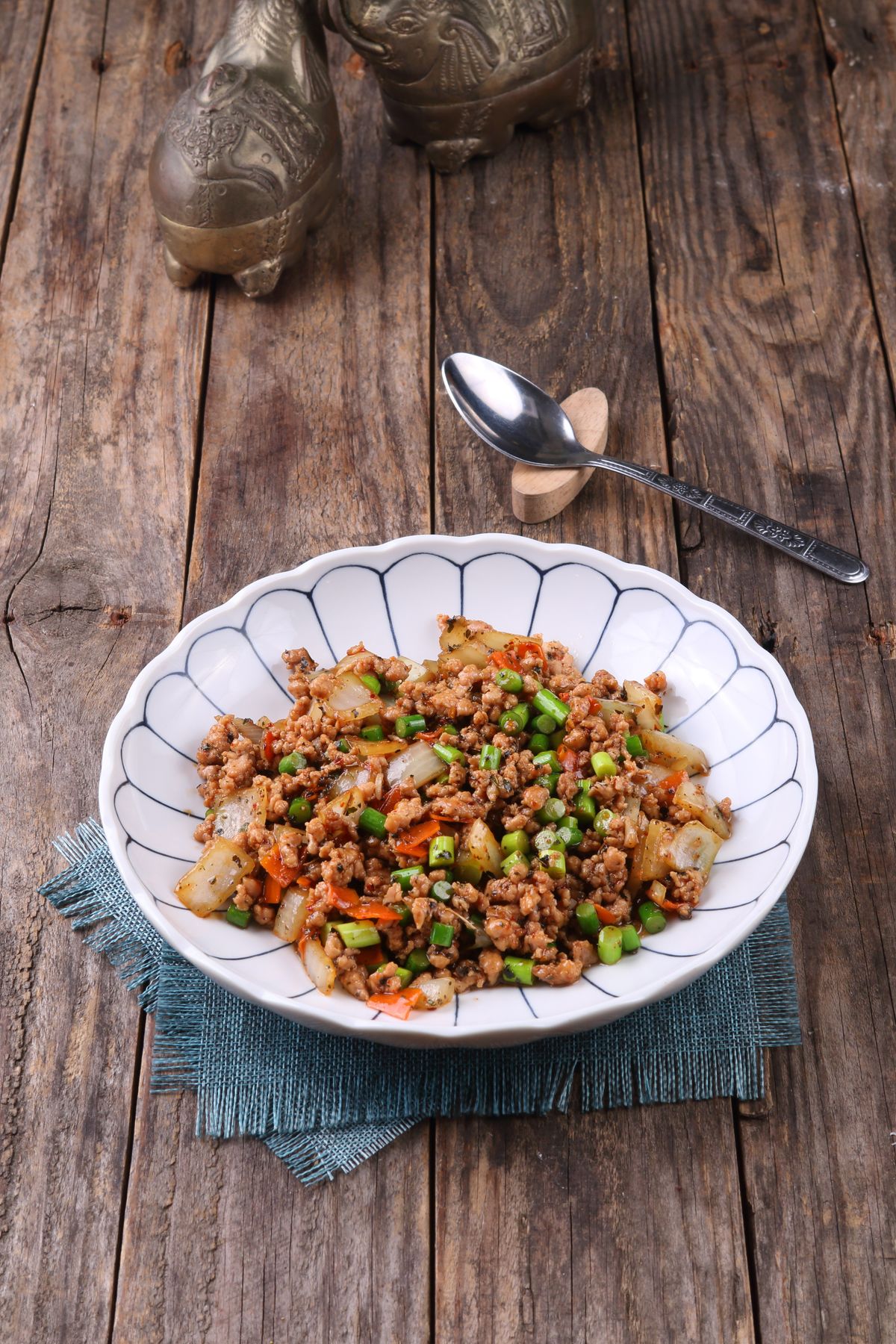 Bowl of savory Thai minced meat with fresh herbs on a rustic wood surface — the signature look of chicken larb.
