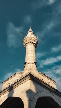 A stunning view of a mosque minaret reaching into a clear blue sky with birds flying around.