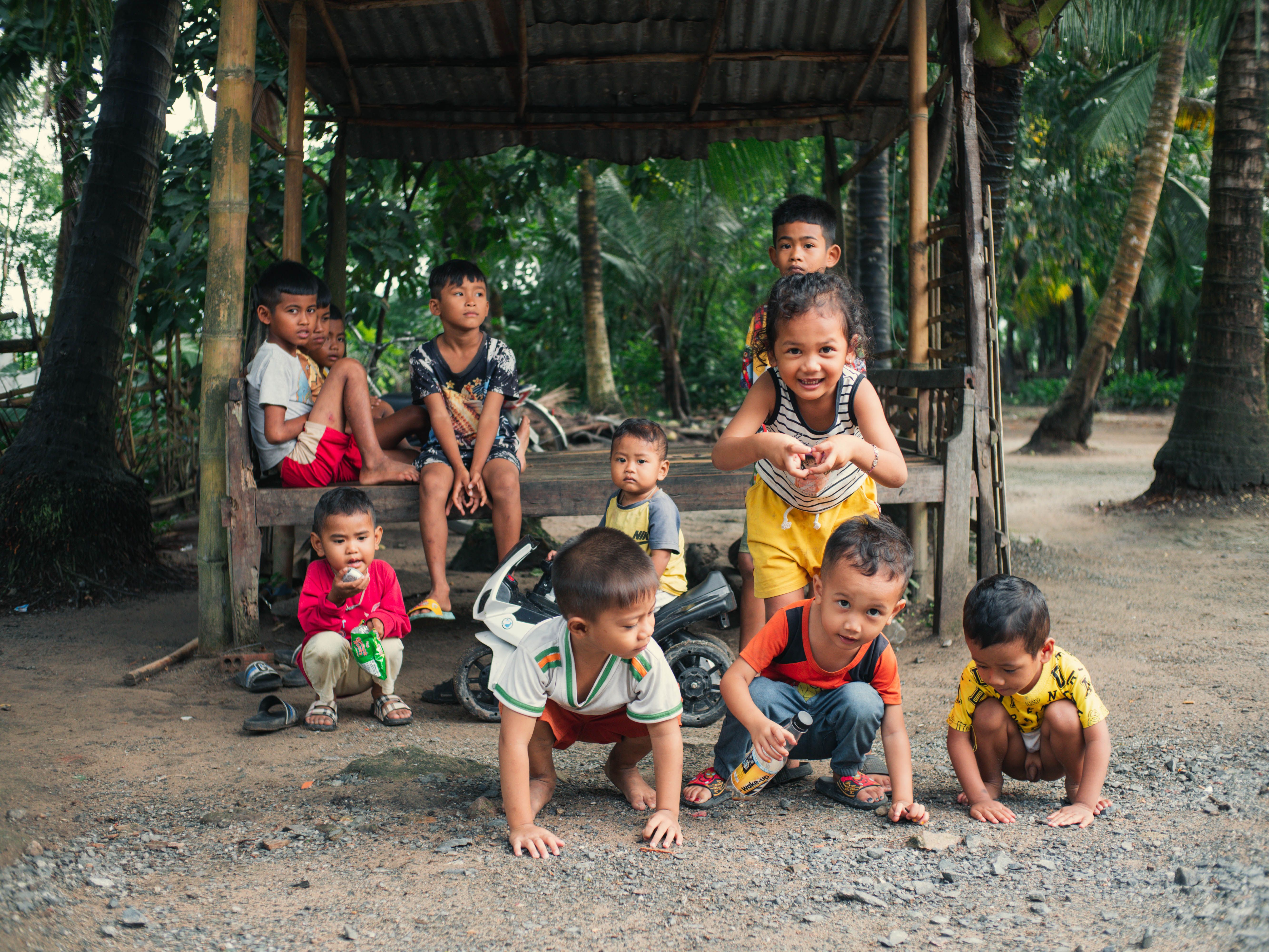 Group of Vietnamese children playing under a hut in a rural area, capturing joyful moments outdoors.
