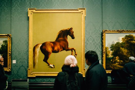 Visitors view a majestic horse painting at a museum, showcasing art appreciation and cultural exploration., free online jigsaw puzzle on JigsawPuzzlesFreeOnline.org