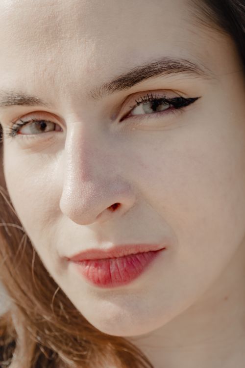 Free Detailed close-up portrait highlighting a young woman's natural beauty in daylight. Stock Photo