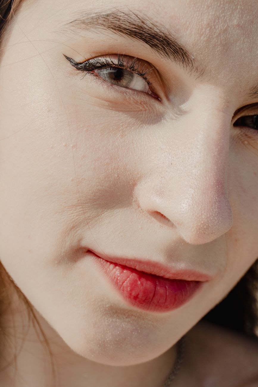 Detailed close-up of a woman's face showing red lips and winged eyeliner.