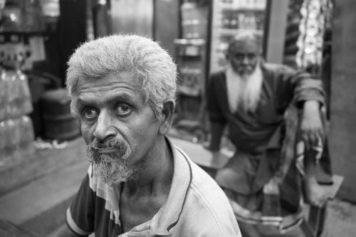Free Black and white street photography capturing two men at a tea stall in Dhaka, Bangladesh. Stock Photo