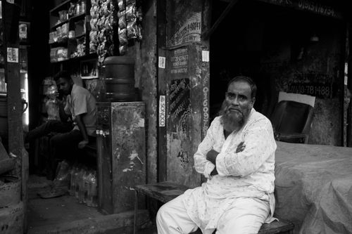 Free A traditional teastall in Dhaka with an elderly man sitting, capturing a moment of daily life. Stock Photo