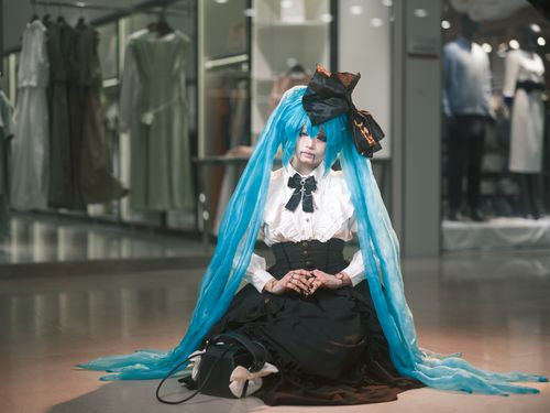 Free Cosplayer wearing elaborate Gothic Lolita outfit with long blue wig in a mall setting. Stock Photo