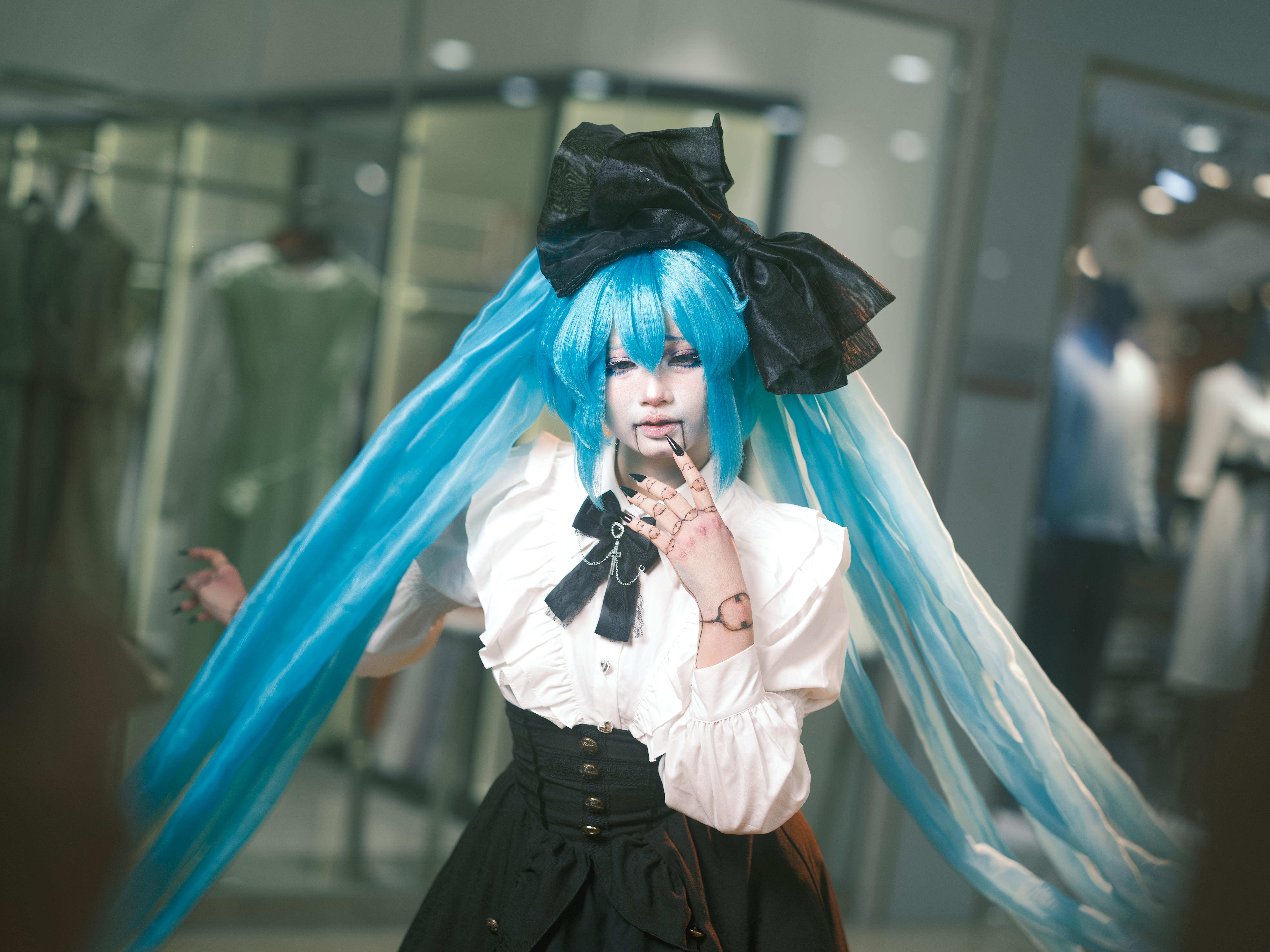 A cosplayer in a detailed anime costume poses confidently in an indoor setting, showcasing vibrant colors and style.