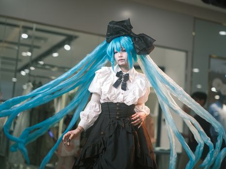Cosplayer in elaborate costume with striking blue hair, dressed as a popular animated character.
