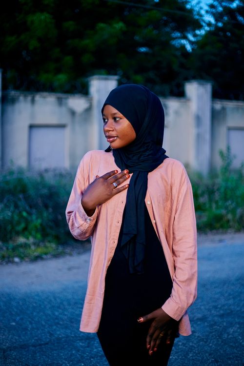 Free Portrait of a young woman wearing a hijab standing outdoors, with a serene background. Stock Photo