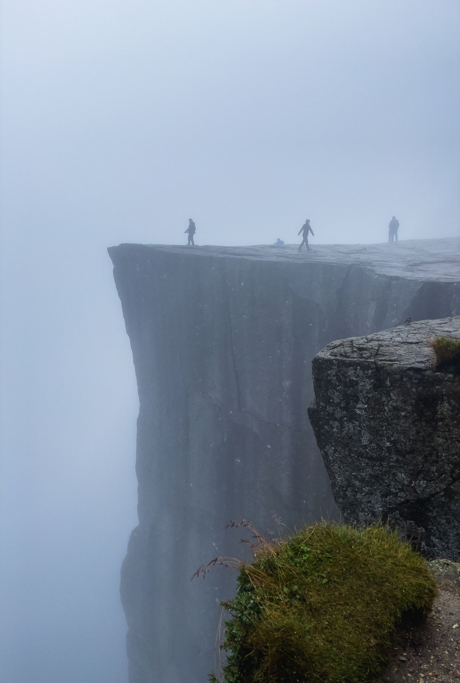 Mist swirling around the sheer edge of Preikestolen high above the Lysefjord