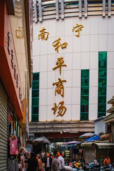 View of a busy street market entrance in Asia with people and shops in vibrant setting.