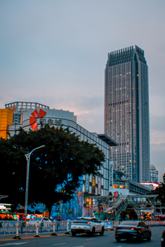 Urban skyline featuring a tall skyscraper and busy streets at twilight.