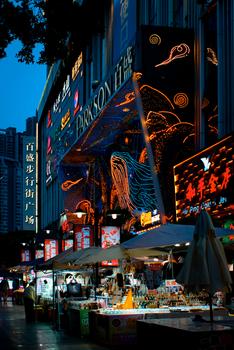 Vibrant night street market scene with colorful neon signs and lively atmosphere.