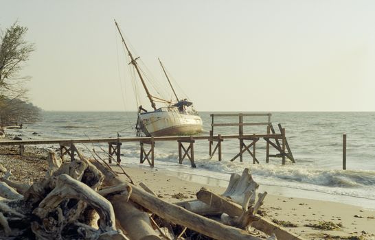 An aged shipwreck leaning on a pier at Snaptun beach in Denmark, evoking a rustic and nostalgic scene.