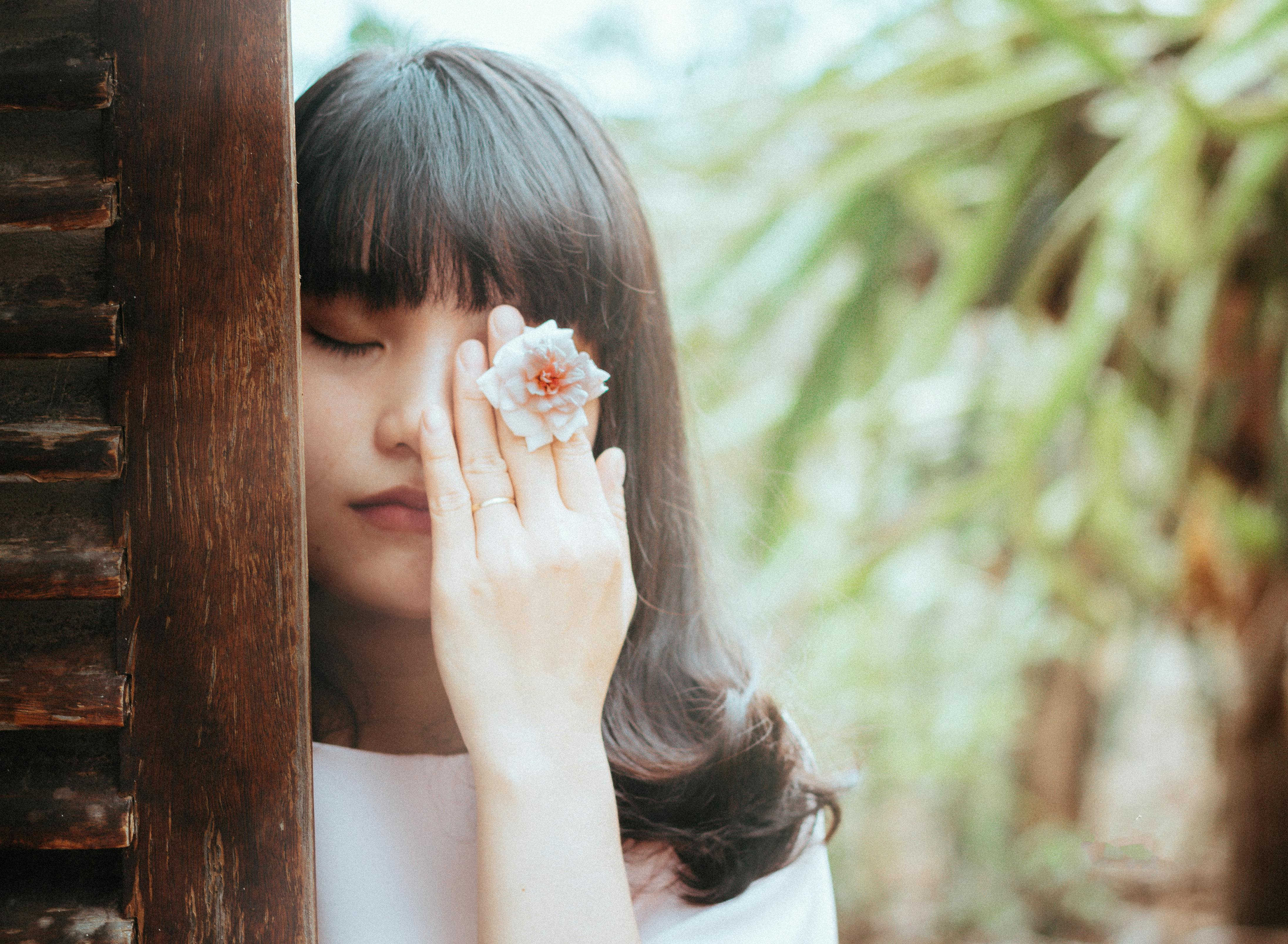 A tranquil portrait of a woman with a flower, set against a natural backdrop in Kon Tum, Vietnam.