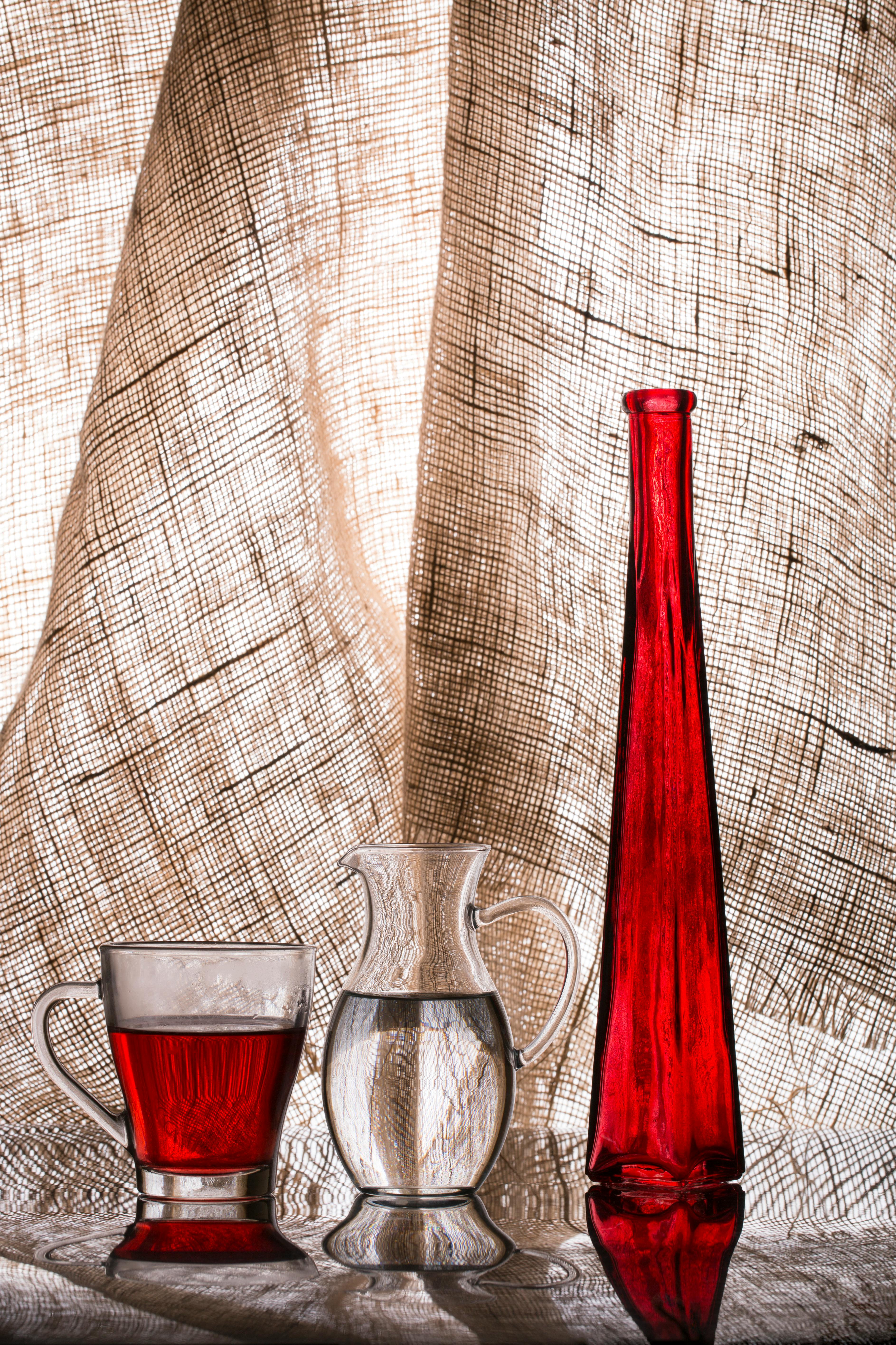 Artistic arrangement of red glass items against textured fabric background, creating a vibrant contrast.