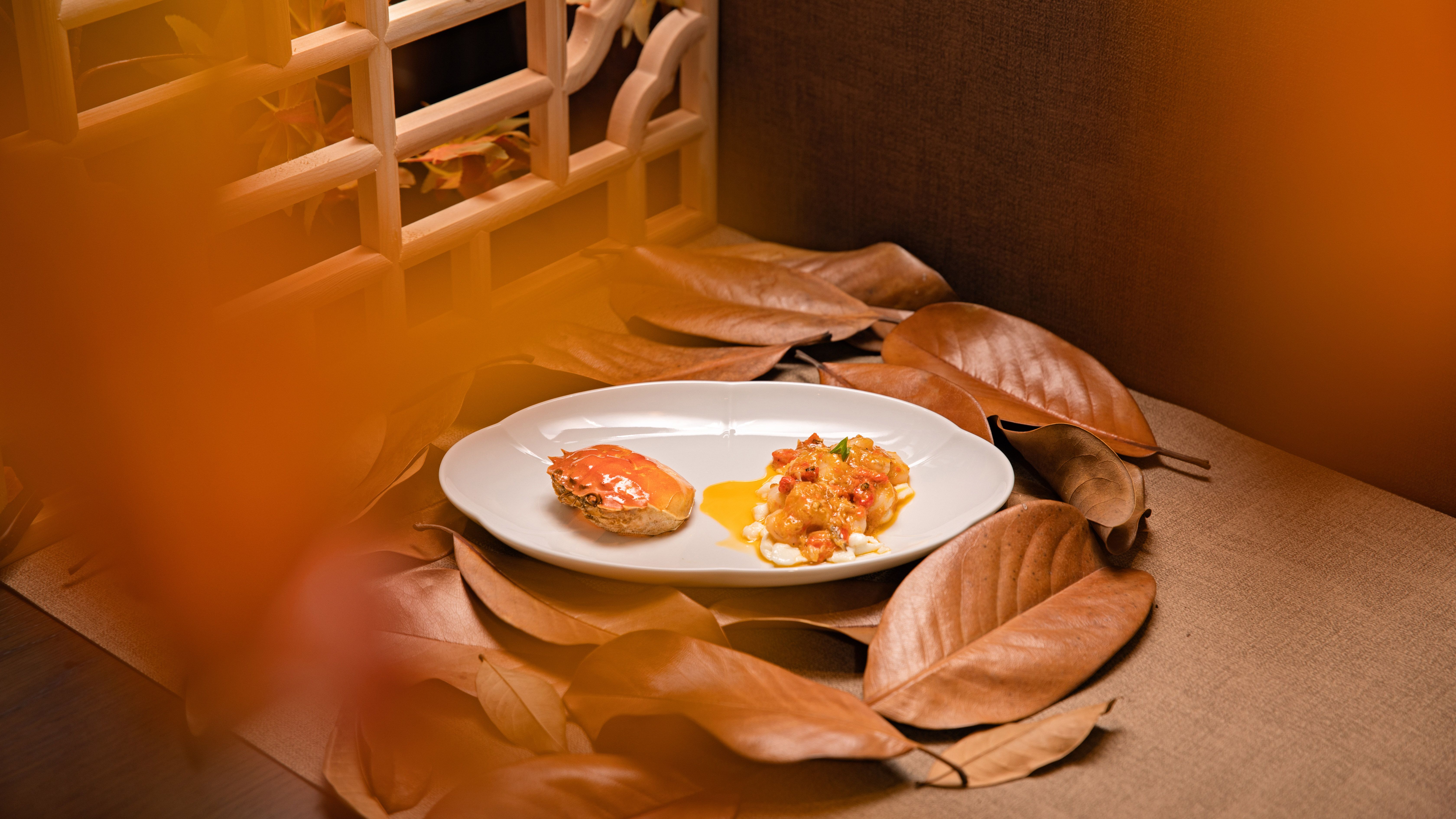 Gourmet dish elegantly plated with autumn leaves and warm orange lighting, evoking a cozy, seasonal atmosphere.