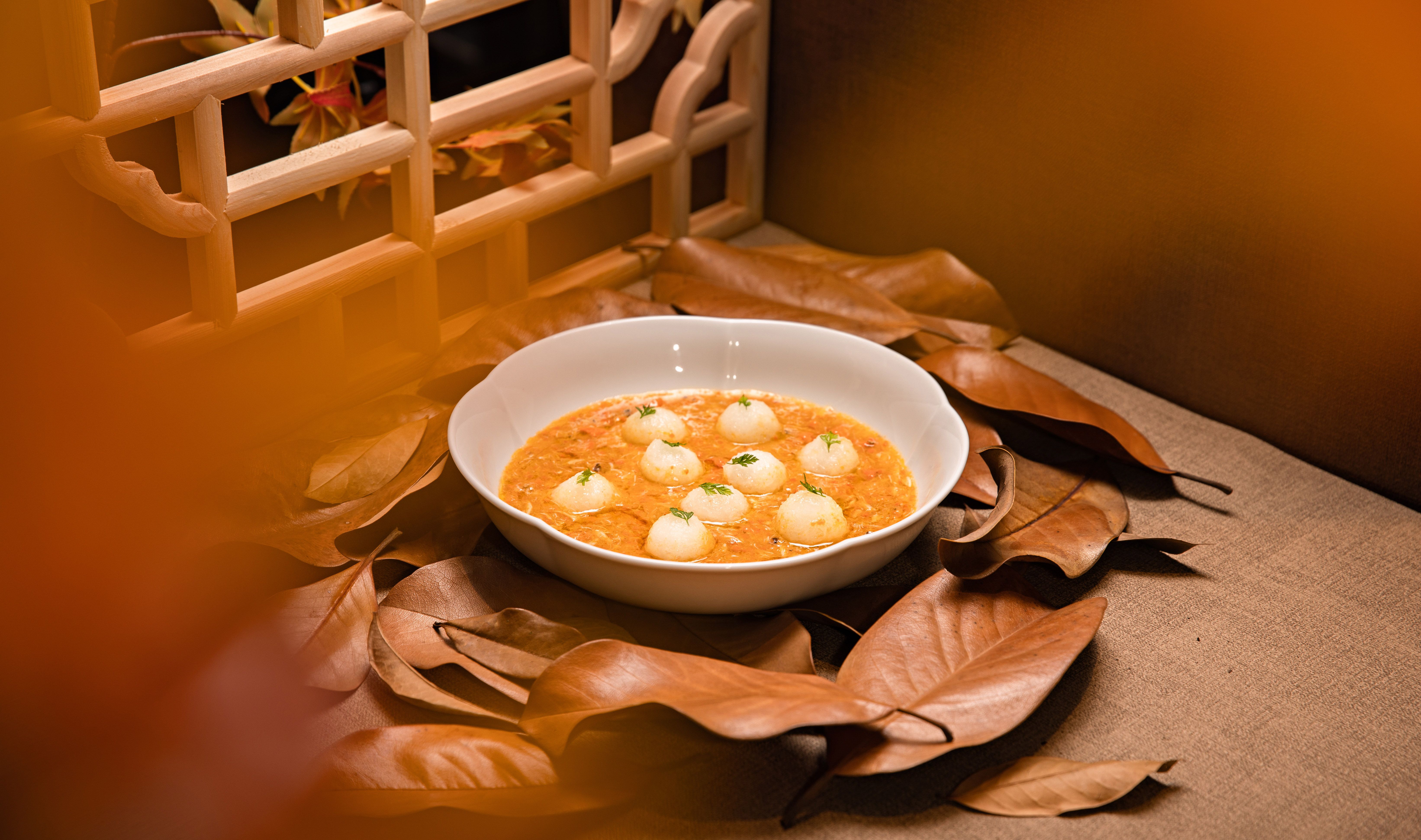 a bowl of fufu and groundnut soup with a waterfall visible in the background