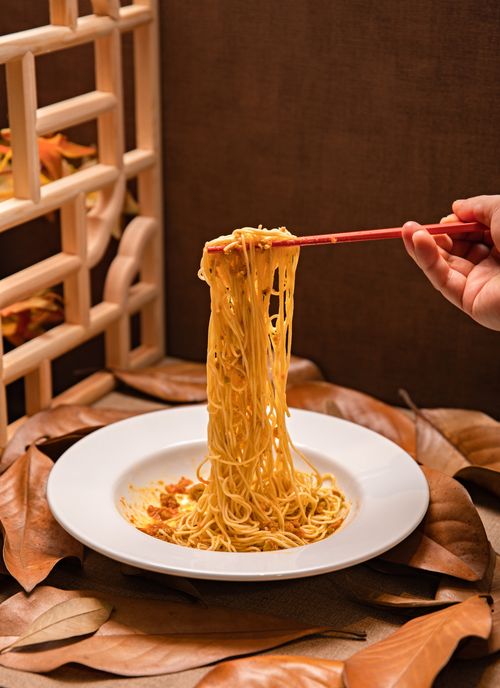Free Enjoy a savory dish of Asian noodles lifted with chopsticks, surrounded by autumn leaves. Stock Photo
