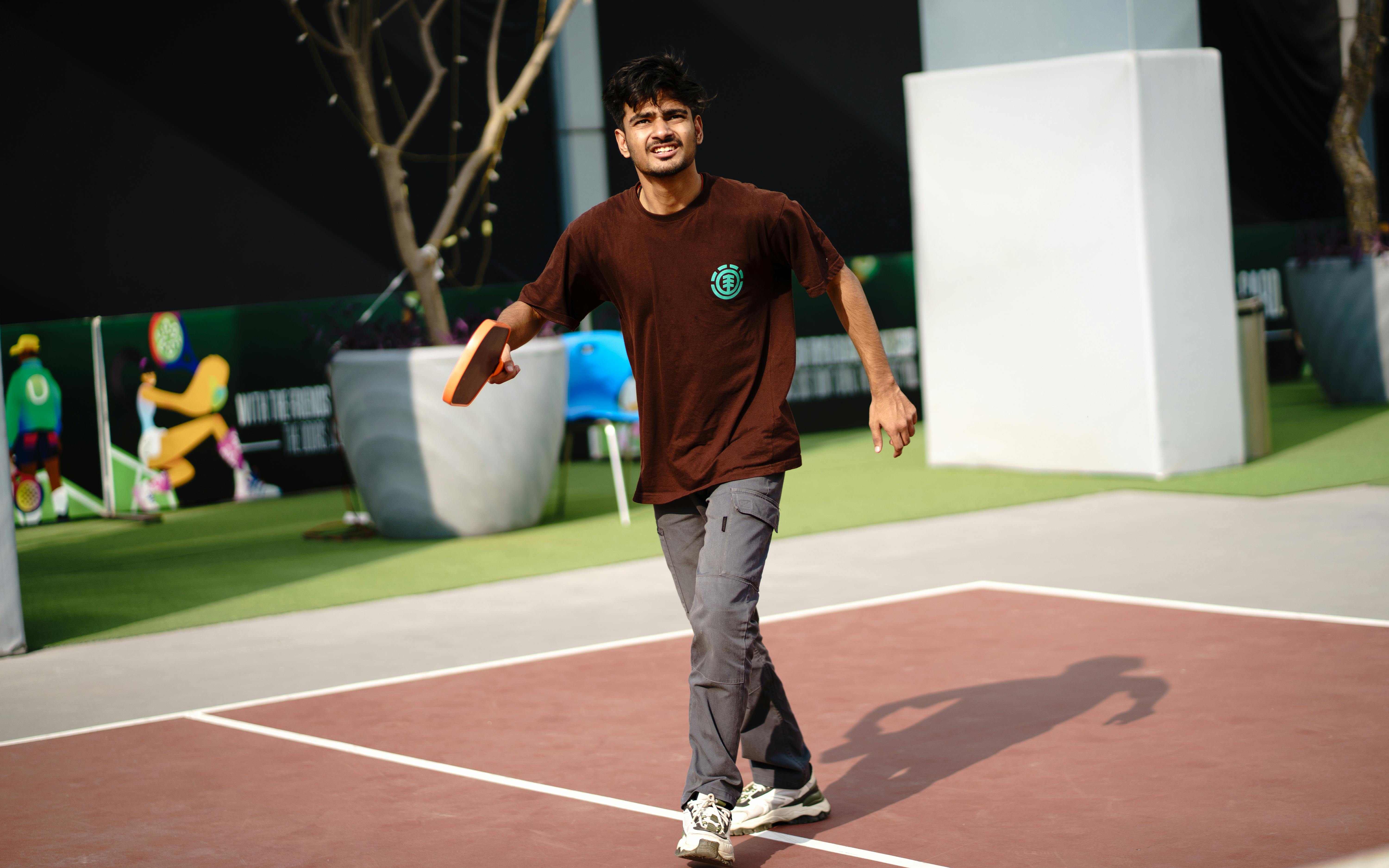 A young man playing pickleball outdoors, showcasing active lifestyle and fitness.