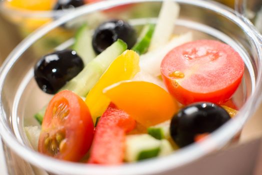 Close-up of a fresh vegetable salad with tomatoes, cucumber, olives, and peppers.